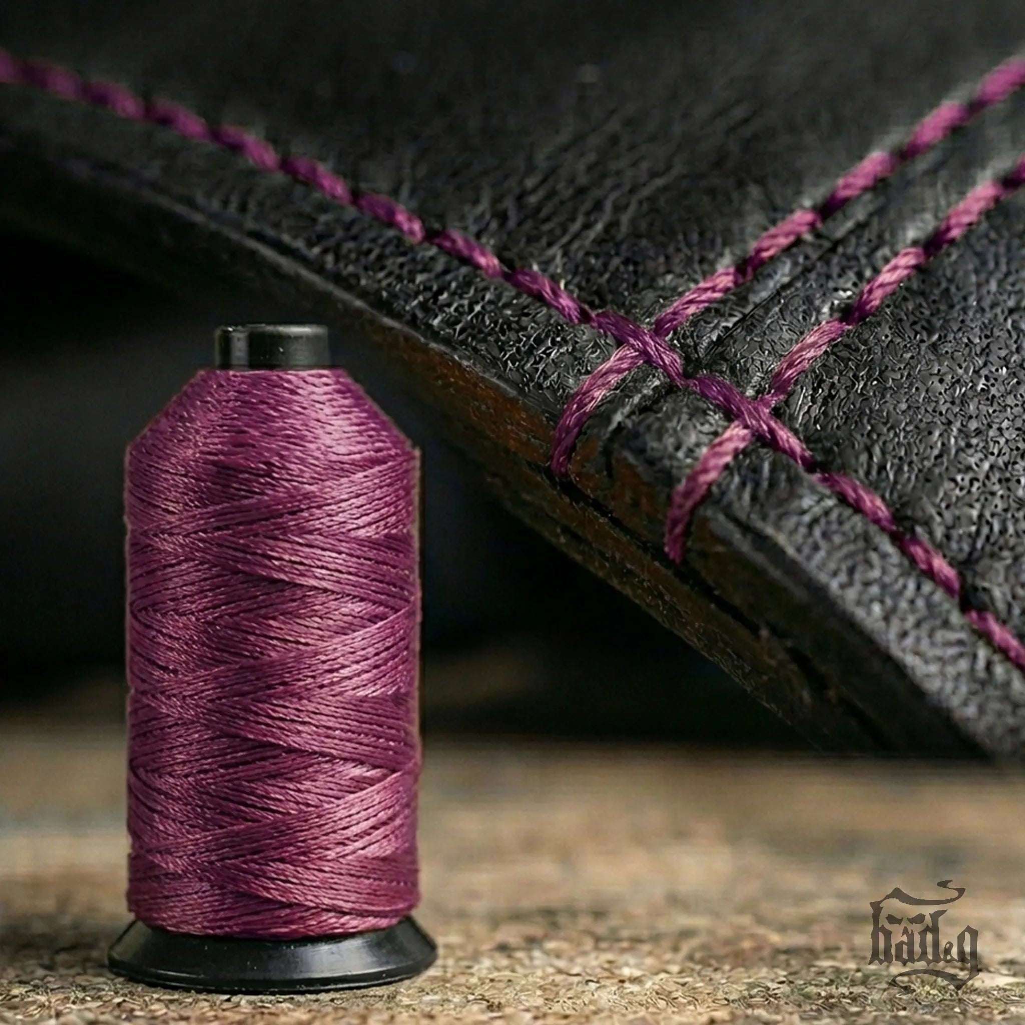 Spool of purple thread next to a leather product with purple stitching